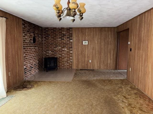 9050 N State Route 49, Greenville, OH 45331 - unfurnished living room with wood walls, carpet, a chandelier, a wood stove, and a textured ceiling
