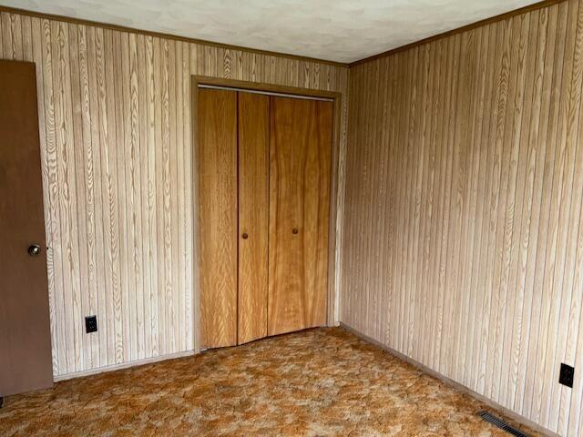 9050 N State Route 49, Greenville, OH 45331 - unfurnished bedroom featuring a closet, wooden walls, and carpet flooring