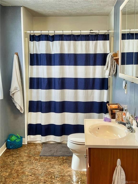 bathroom featuring vanity, toilet, curtained shower, and a textured ceiling