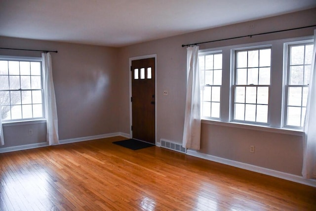 foyer entrance featuring light wood-style floors, a wealth of natural light, and visible vents