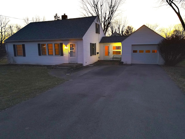 view of front facade with roof with shingles, a chimney, aphalt driveway, and a yard