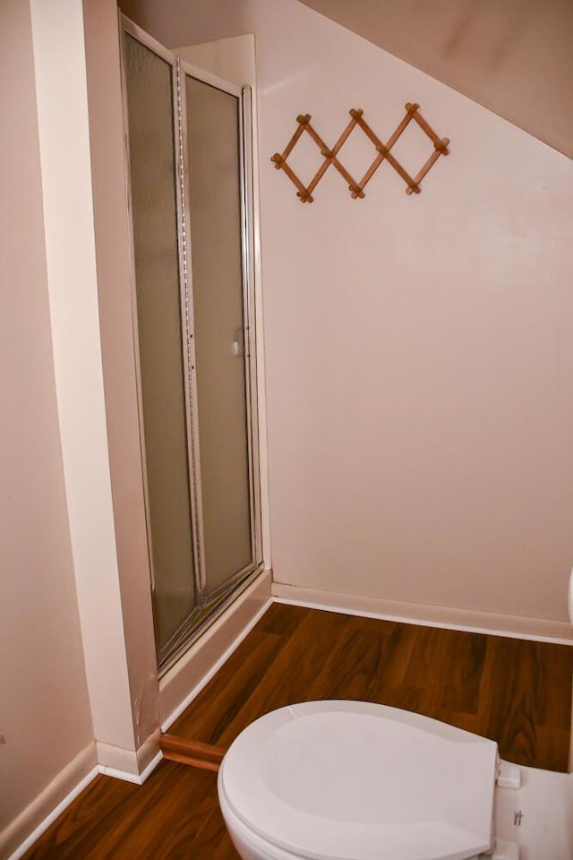 bathroom featuring wood finished floors, a shower stall, toilet, and baseboards