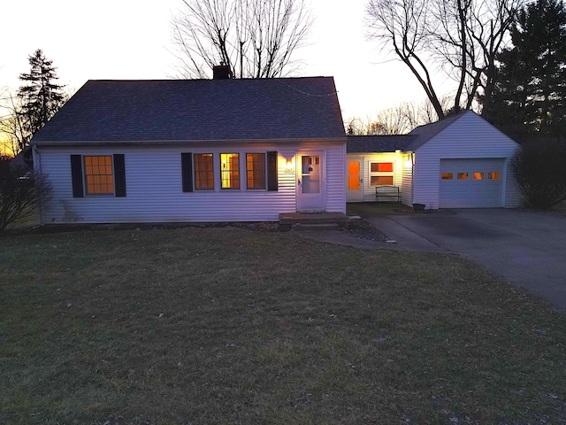 view of front of property featuring a garage, a yard, driveway, and a shingled roof