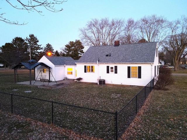 back of house with a patio, central AC unit, a fenced backyard, roof with shingles, and a chimney