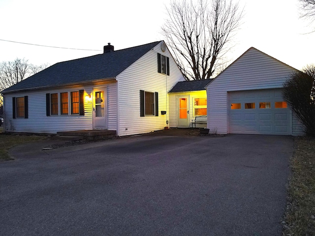 view of front of property featuring a garage, driveway, and a chimney