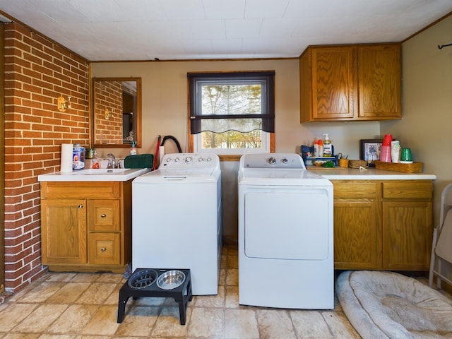 laundry room with sink, cabinets, brick wall, and separate washer and dryer