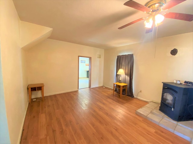 116 N Mill St, De Graff, OH 43318 - unfurnished living room with a wood stove, ceiling fan, wood finished floors, and baseboards
