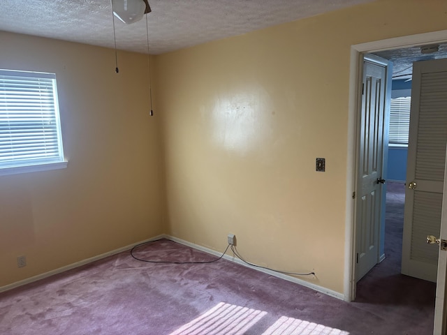 carpeted spare room featuring baseboards and a textured ceiling