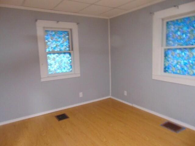 unfurnished room with hardwood / wood-style flooring and a drop ceiling