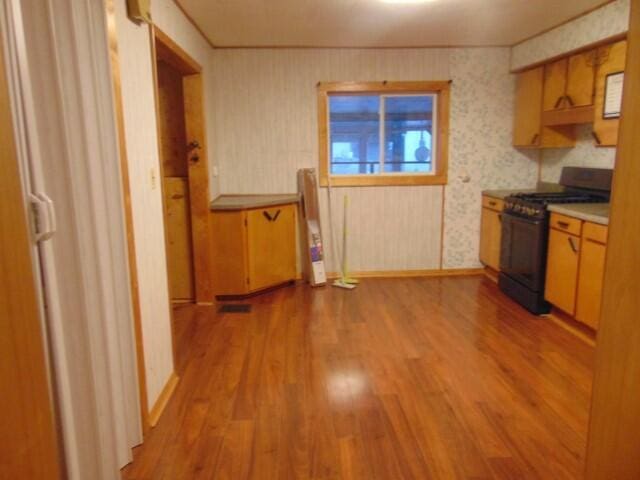 kitchen featuring crown molding, black range with gas stovetop, a barn door, and wood-type flooring