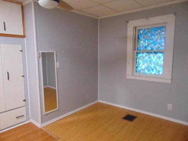 unfurnished room with a drop ceiling, ceiling fan, and light hardwood / wood-style flooring