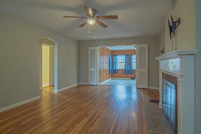 unfurnished living room featuring hardwood / wood-style floors, a fireplace, and ceiling fan