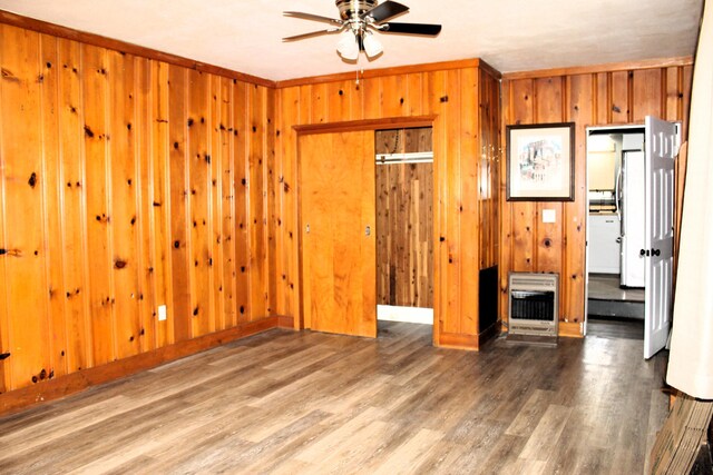 bedroom with crown molding, wooden walls, and wood finished floors