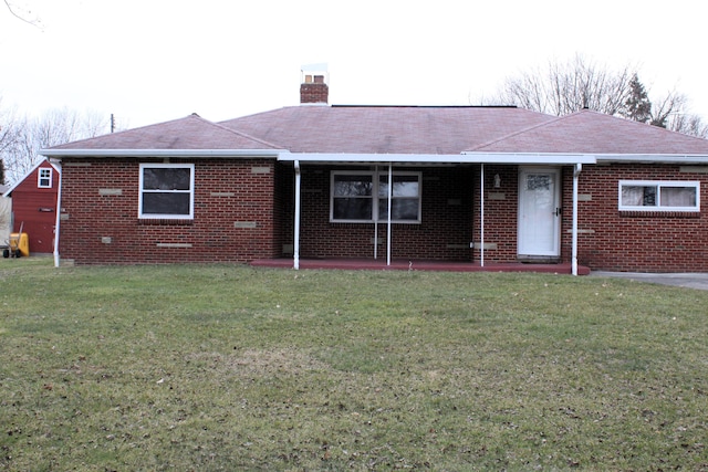 view of front of house with a shingled roof, brick siding, a chimney, and a front lawn