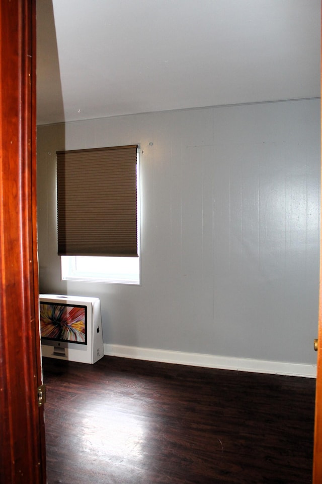 unfurnished room featuring baseboards, heating unit, and wood finished floors