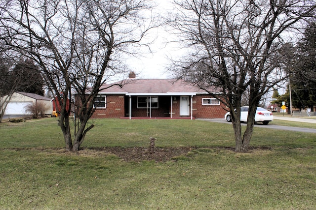 ranch-style home with brick siding, a front lawn, and a chimney