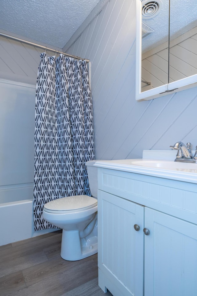 full bathroom with toilet, wood-type flooring, a textured ceiling, vanity, and shower / bath combo