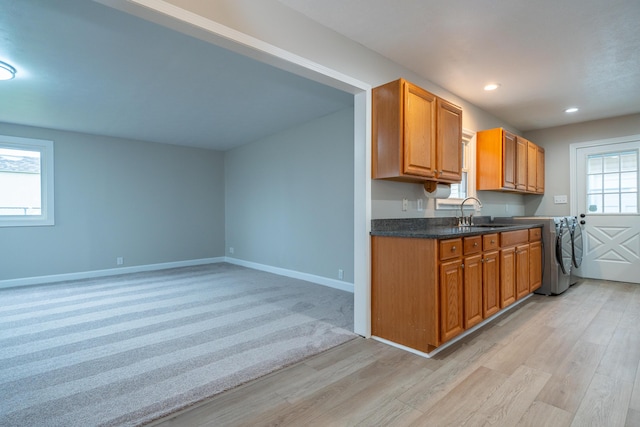 kitchen with sink, washer / dryer, and light hardwood / wood-style flooring