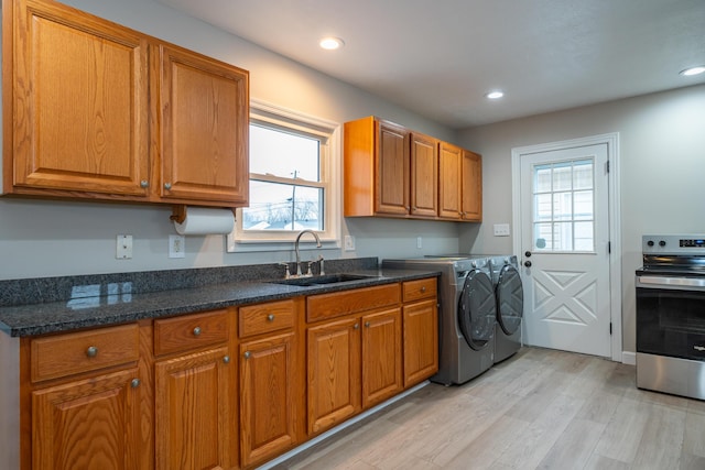 laundry area featuring washing machine and dryer, sink, and light hardwood / wood-style floors