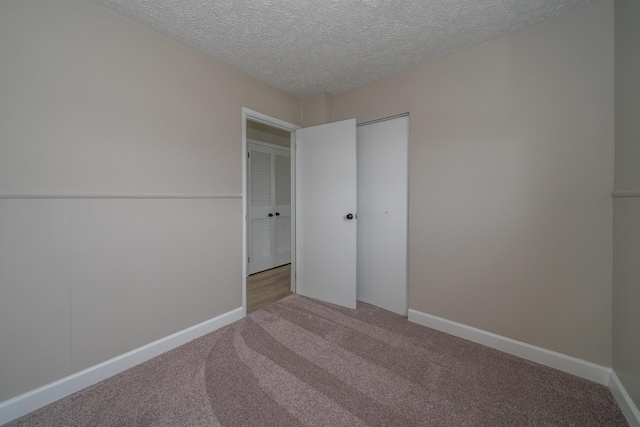 unfurnished bedroom with a closet, light carpet, and a textured ceiling