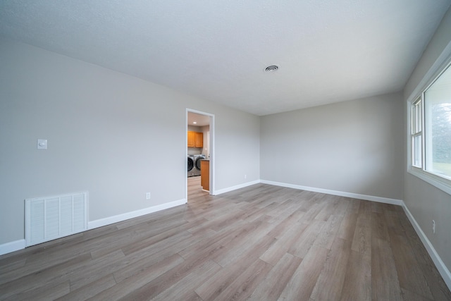 unfurnished room with washer and clothes dryer and light hardwood / wood-style floors