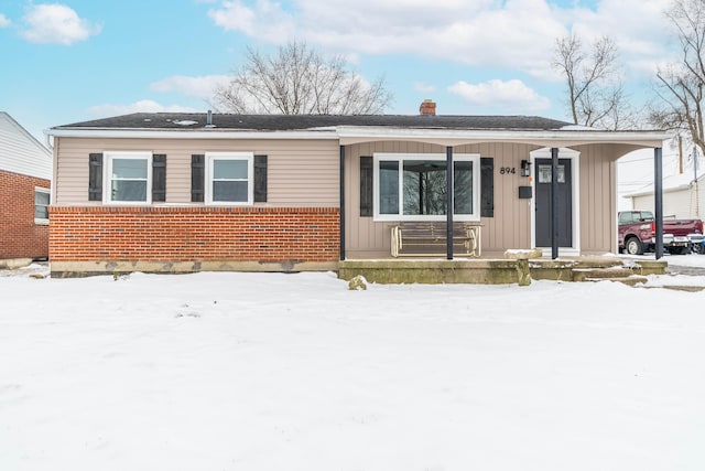 view of front of home with covered porch, brick siding, a chimney, and board and batten siding