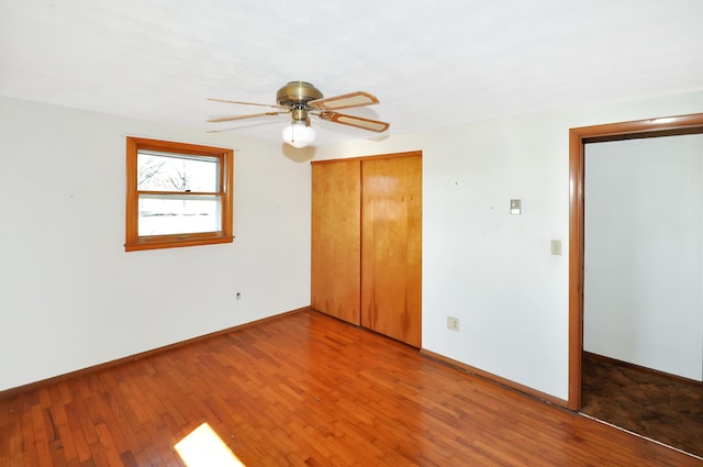 unfurnished bedroom featuring a closet, wood-type flooring, and baseboards