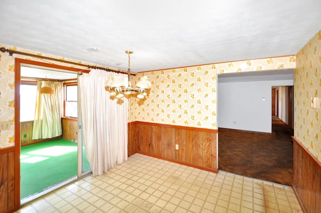 spare room with wainscoting, wallpapered walls, and light floors