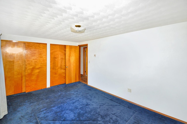 unfurnished bedroom with multiple closets, a textured ceiling, and carpet floors