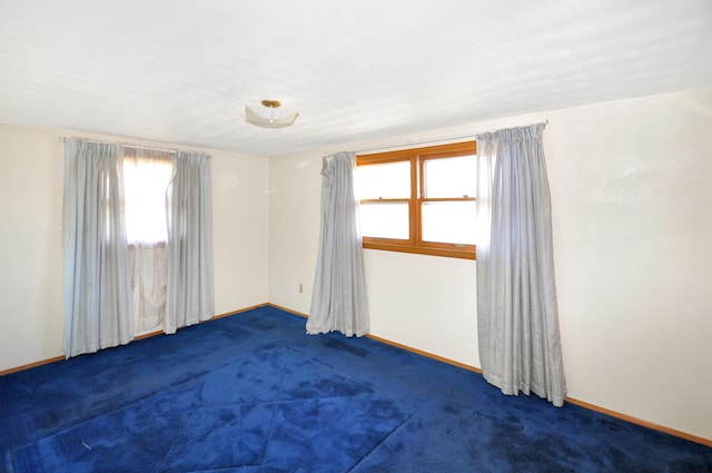 unfurnished room featuring carpet and baseboards