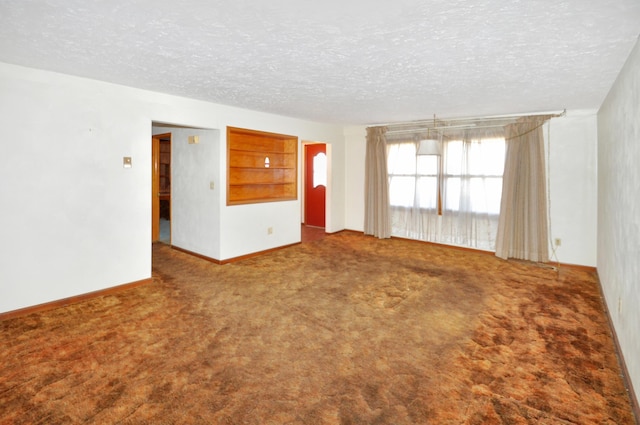 unfurnished room with carpet flooring, built in shelves, a textured ceiling, and baseboards