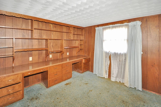 unfurnished office with built in desk, carpet, and wooden walls