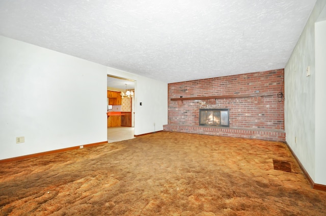 unfurnished living room with baseboards, carpet floors, a fireplace, a notable chandelier, and a textured ceiling