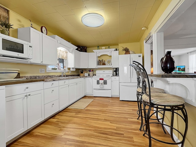 kitchen with white cabinetry, white appliances, plenty of natural light, and light wood-type flooring