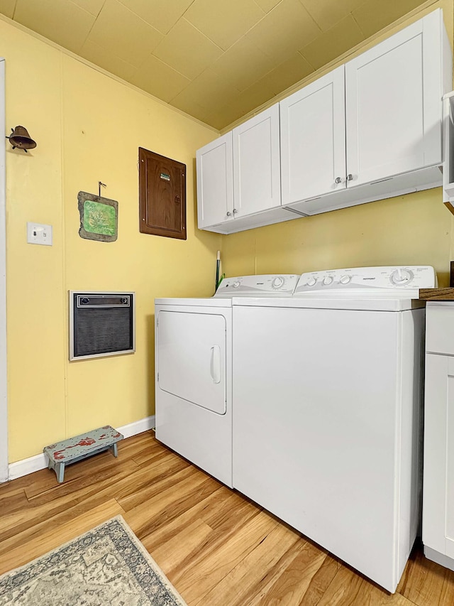 washroom with heating unit, cabinets, washer and dryer, and light hardwood / wood-style flooring