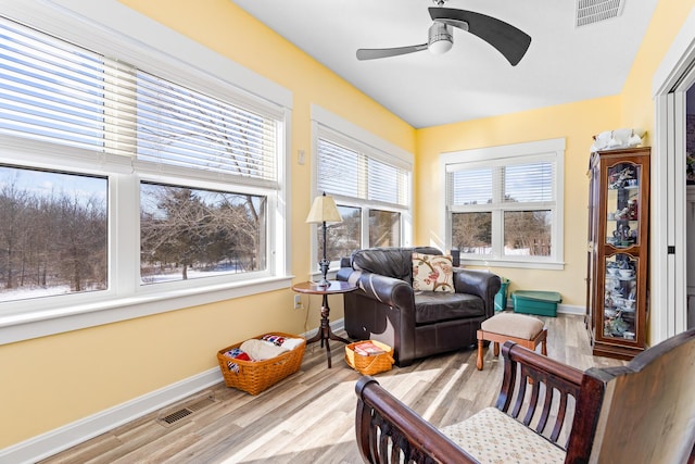 sitting room with a ceiling fan, light wood-type flooring, visible vents, and baseboards