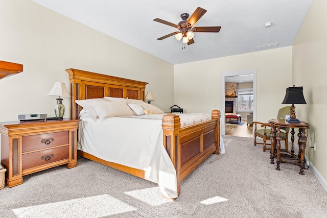 bedroom with visible vents, a large fireplace, light carpet, ceiling fan, and baseboards