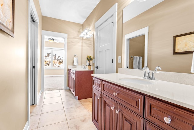 bathroom featuring tile patterned flooring, two vanities, a sink, and baseboards