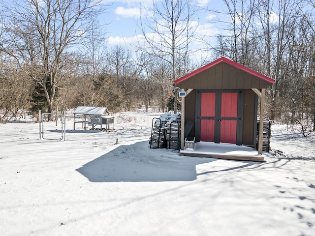 snow covered structure with a storage shed and an outdoor structure