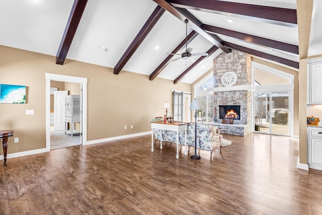 living area with baseboards, ceiling fan, wood finished floors, a fireplace, and beam ceiling