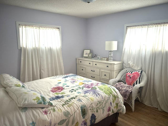bedroom with multiple windows, wood finished floors, and a textured ceiling