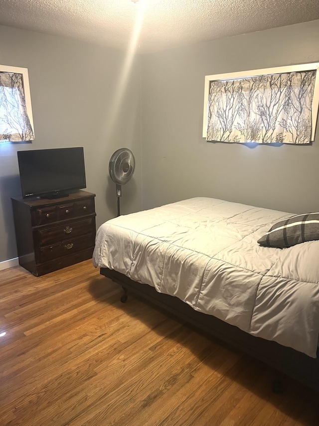 bedroom with a textured ceiling and wood finished floors