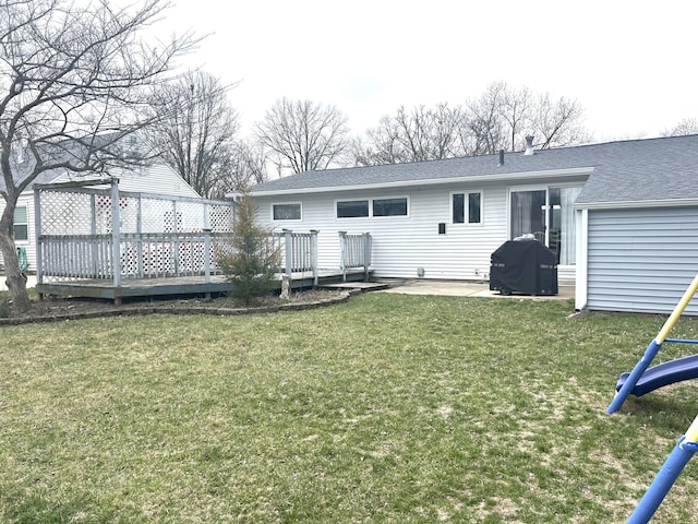back of property with a lawn, a wooden deck, a patio area, and roof with shingles