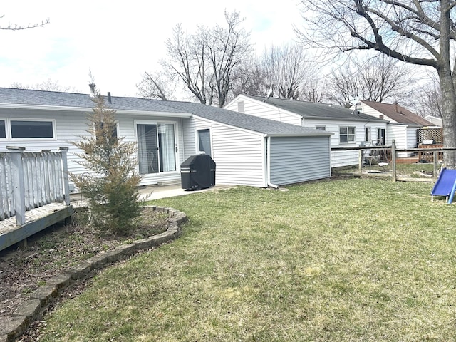 back of house featuring a shingled roof, fence, and a yard