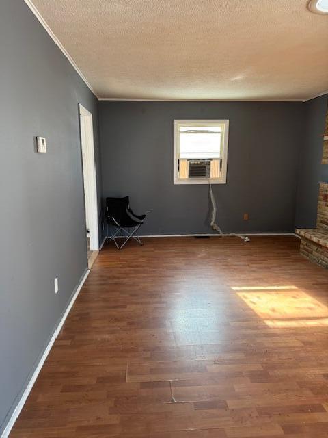 empty room with dark wood-type flooring, cooling unit, a textured ceiling, and baseboards