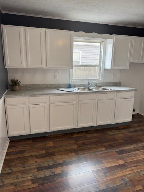 kitchen featuring white cabinets, dark wood-style flooring, light countertops, a textured ceiling, and a sink