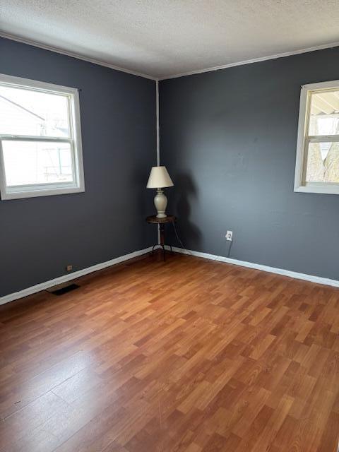 empty room featuring a textured ceiling, wood finished floors, and a healthy amount of sunlight