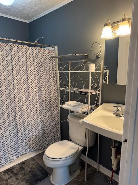 bathroom featuring crown molding, toilet, a sink, a textured ceiling, and tile patterned floors