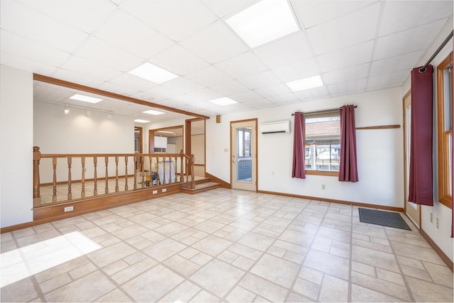 7868 Beech Ave, Russells Point, OH 43348 - empty room with a wall mounted air conditioner, baseboards, a drop ceiling, and stairway