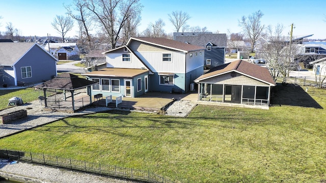 back of property with a patio area, a residential view, fence, and a sunroom